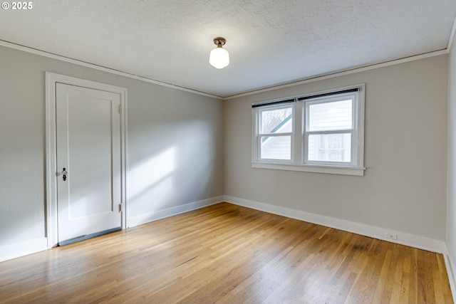 spare room featuring crown molding, a textured ceiling, and light wood-type flooring