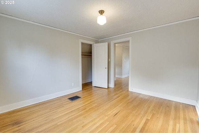 unfurnished bedroom featuring crown molding, light hardwood / wood-style floors, and a closet