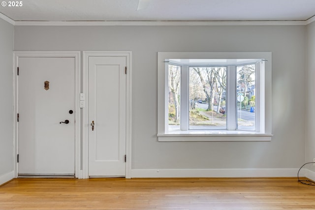 entryway with ornamental molding and light hardwood / wood-style floors