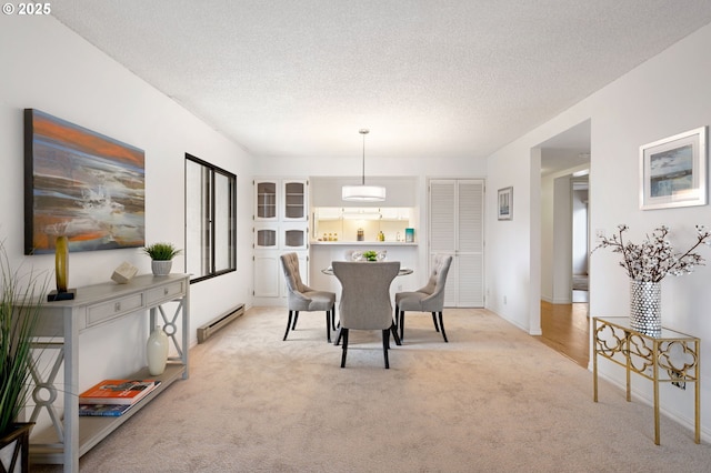 dining space with baseboard heating, light colored carpet, and a textured ceiling