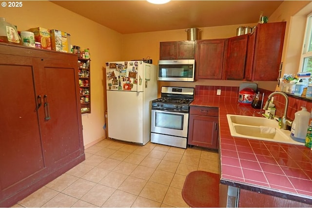 66663 Gunderson Rd, North Bend, OR 97459 - kitchen featuring stainless steel appliances, tile countertops, light tile patterned flooring, and brown cabinets