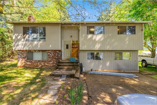 raised ranch with brick siding, a chimney, and entry steps