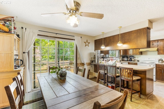dining room with a healthy amount of sunlight, light tile patterned floors, a ceiling fan, and a textured ceiling