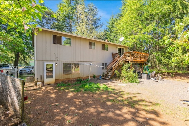 rear view of house with stairway, a deck, and fence
