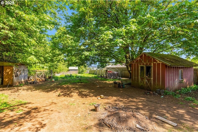 view of yard featuring an outdoor structure, fence, and a storage shed