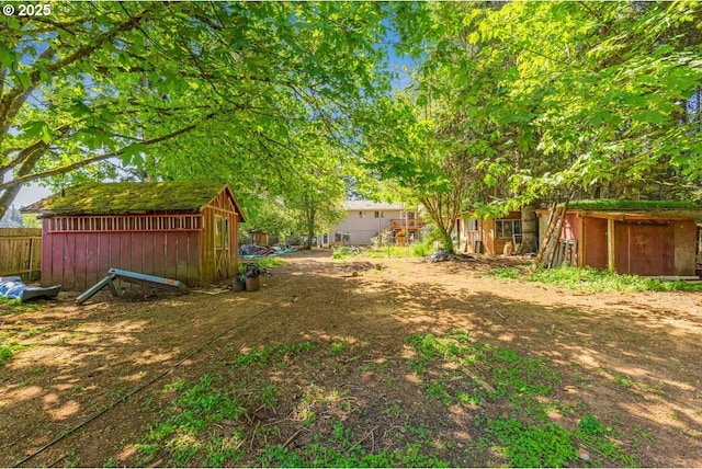 view of yard featuring fence, a storage unit, and an outdoor structure
