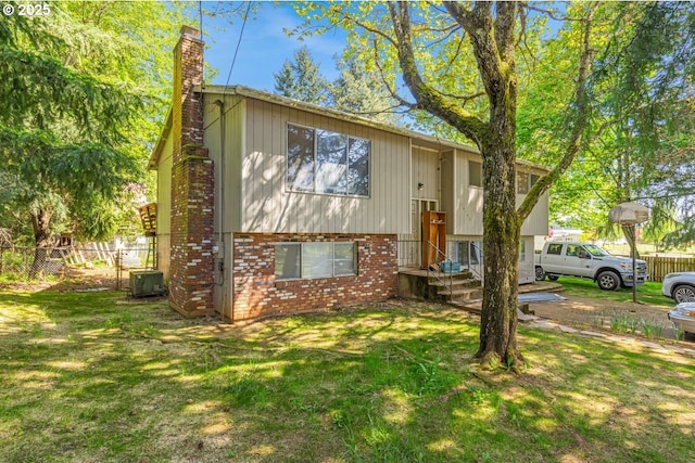 bi-level home with fence, a chimney, a front yard, and brick siding
