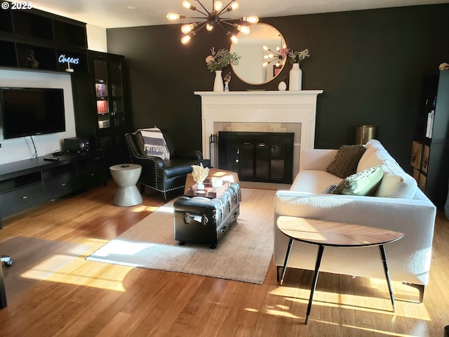 living room featuring light hardwood / wood-style floors, a tile fireplace, and an inviting chandelier