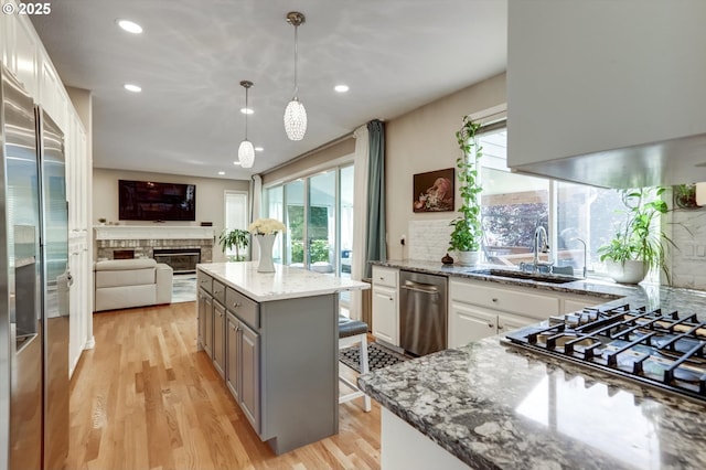 15463 NW Andalusian Way, Portland, OR 97229 - kitchen featuring a sink, plenty of natural light, light wood-type flooring, a glass covered fireplace, and recessed lighting