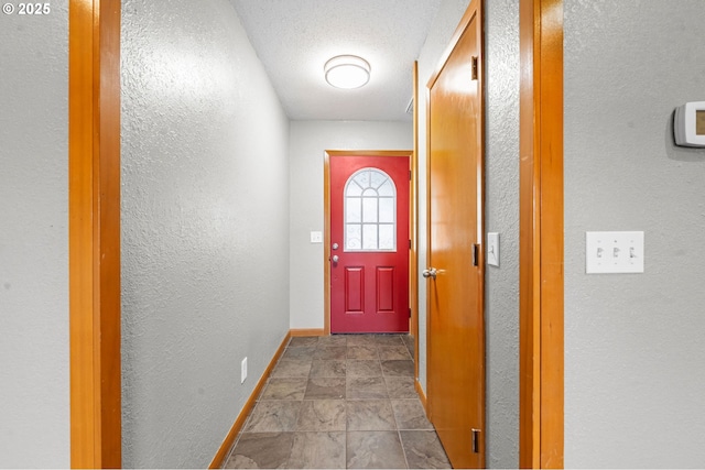 1313 Wakeman Ln, Gearhart, OR 97138 - doorway to outside featuring baseboards, a textured wall, stone finish flooring, and a textured ceiling
