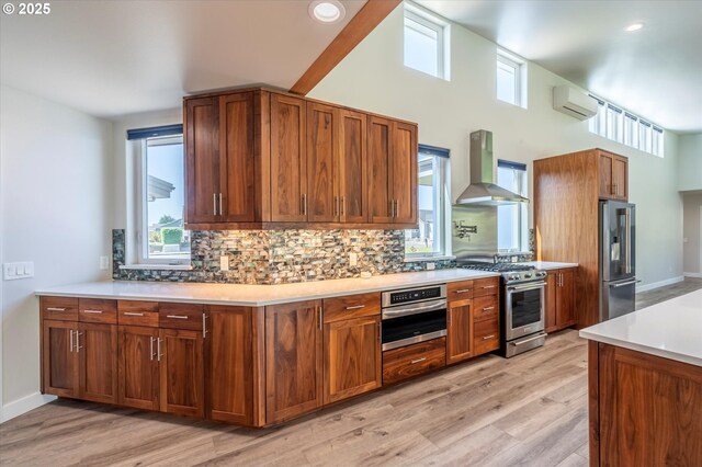 760 Carter St SW, Bandon, OR 97411 - kitchen featuring wall chimney range hood, stainless steel appliances, decorative backsplash, light wood-type flooring, and recessed lighting