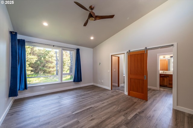 760 Carter St SW, Bandon, OR 97411 - unfurnished bedroom with a barn door, high vaulted ceiling, wood finished floors, baseboards, and recessed lighting