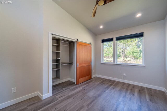 760 Carter St SW, Bandon, OR 97411 - unfurnished bedroom with baseboards, wood finished floors, lofted ceiling, a barn door, and a closet