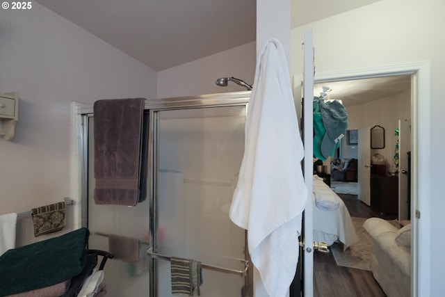 bathroom with hardwood / wood-style flooring, lofted ceiling, and a shower with shower door