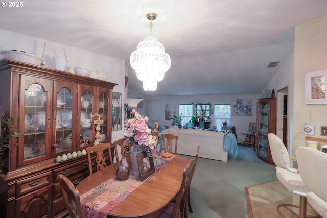 dining room featuring lofted ceiling, carpet, and an inviting chandelier