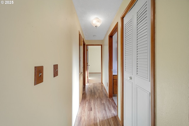 hall with a textured ceiling and light hardwood / wood-style floors