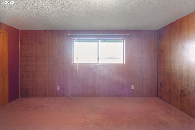 empty room with carpet, wood walls, and a textured ceiling