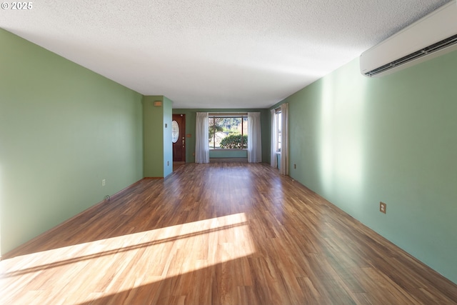 unfurnished living room with dark hardwood / wood-style flooring, an AC wall unit, and a textured ceiling