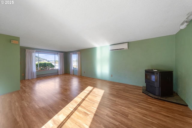 spare room with wood-type flooring, a baseboard heating unit, a wood stove, and an AC wall unit