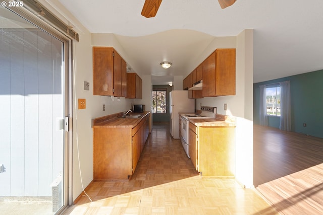 kitchen with white appliances, light parquet floors, ceiling fan, and sink