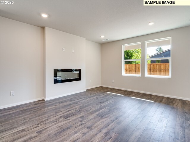 2133 NE 4th Ave, Battle Ground, WA 98604 - unfurnished living room featuring dark wood-style floors, a glass covered fireplace, baseboards, and recessed lighting