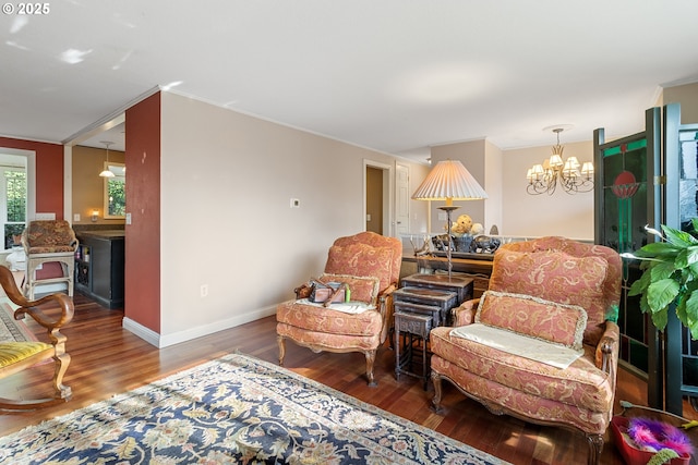 sitting room featuring dark hardwood / wood-style flooring, crown molding, and a chandelier