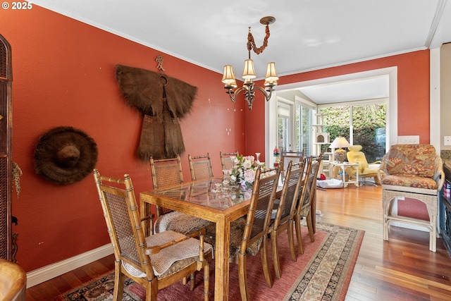 dining room with hardwood / wood-style flooring, ornamental molding, and an inviting chandelier