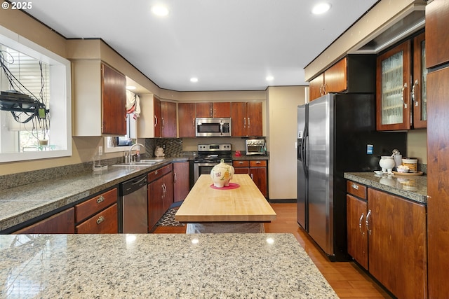 kitchen with stainless steel appliances, sink, wood counters, and light hardwood / wood-style floors