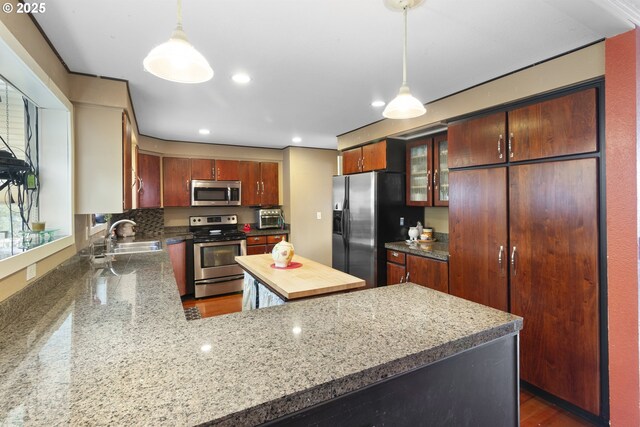 kitchen with appliances with stainless steel finishes, decorative light fixtures, kitchen peninsula, and sink