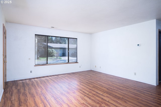 unfurnished room featuring visible vents, baseboards, and wood finished floors