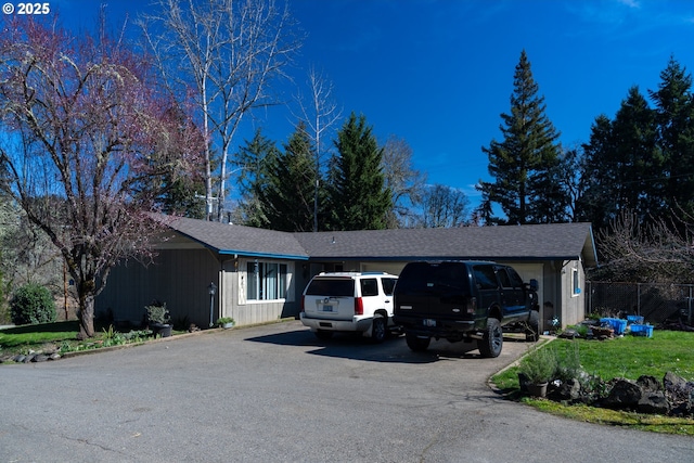 ranch-style house featuring fence, driveway, and a shingled roof