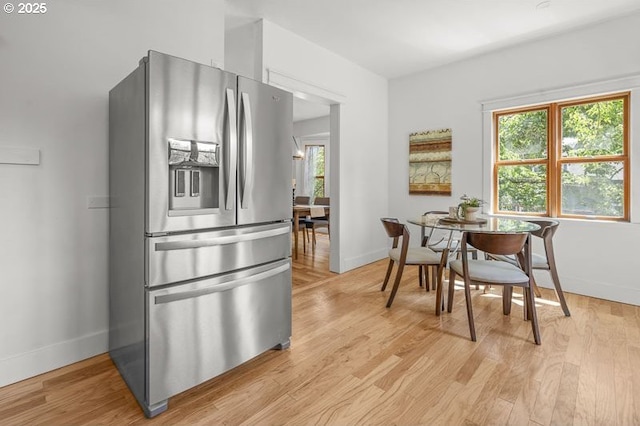 kitchen with stainless steel refrigerator with ice dispenser, baseboards, plenty of natural light, and light wood-style flooring