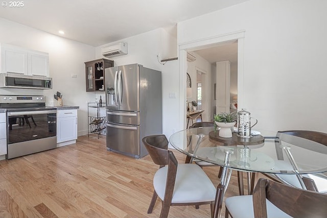 kitchen featuring stainless steel appliances, a wall mounted AC, light wood-style flooring, white cabinetry, and recessed lighting