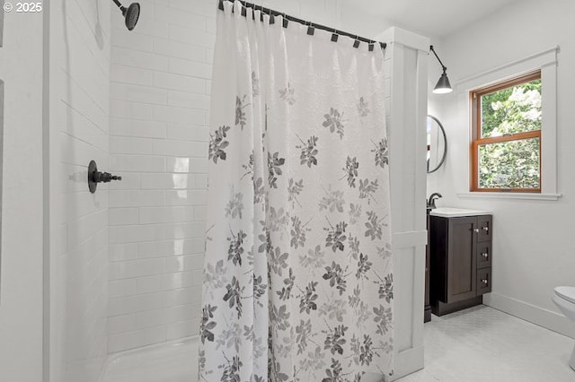 bathroom with a stall shower, vanity, toilet, and baseboards