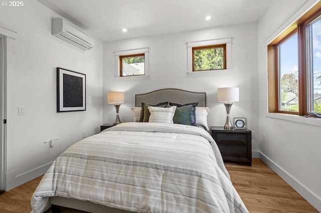 bedroom featuring a wall mounted AC, recessed lighting, wood finished floors, and baseboards