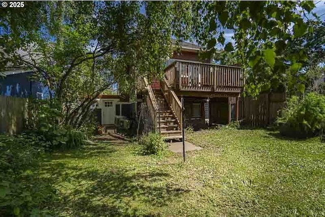 rear view of property featuring a wooden deck, stairway, and a lawn