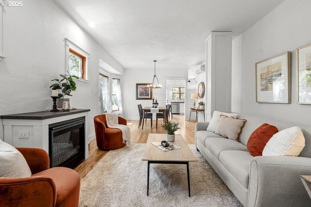 living room with wood finished floors, a glass covered fireplace, and an AC wall unit