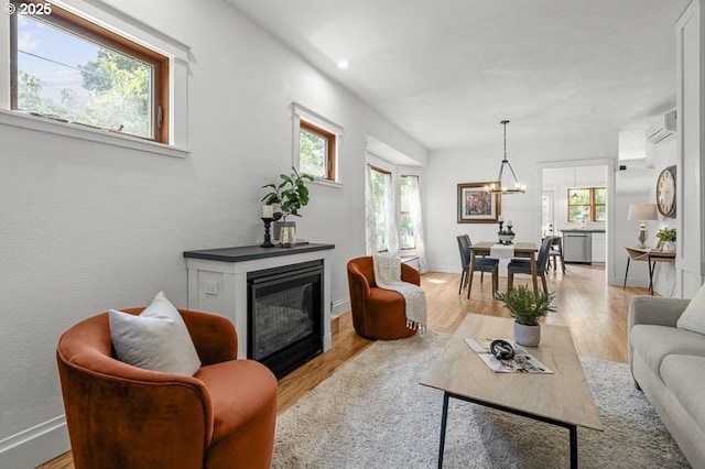 living area featuring wood finished floors, an AC wall unit, and healthy amount of natural light