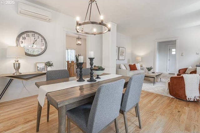 dining space featuring a wall mounted AC, a chandelier, and light wood finished floors