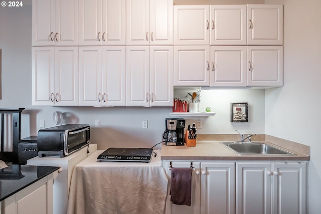 kitchen with white cabinetry, open shelves, and a sink