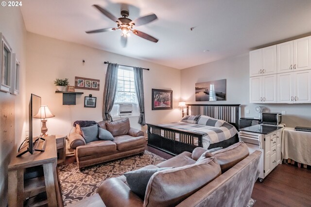 bedroom with cooling unit, dark wood-style floors, and ceiling fan