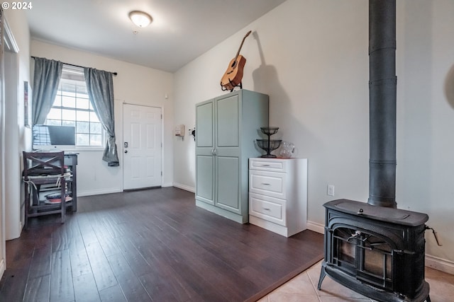 foyer featuring baseboards, a wood stove, and dark wood-style floors