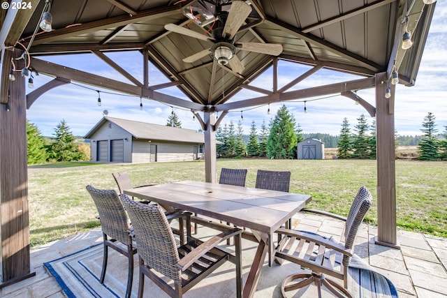 view of patio / terrace with an outbuilding, outdoor dining space, a storage unit, and a garage