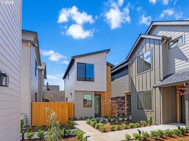 contemporary home featuring board and batten siding and fence