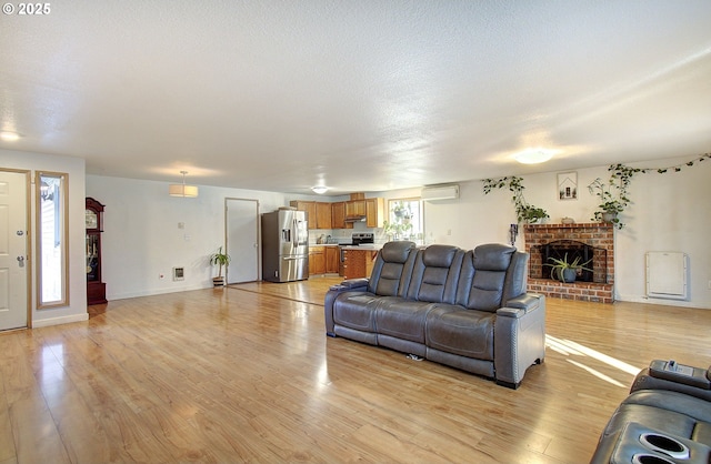 living room featuring light hardwood / wood-style floors, a wall mounted air conditioner, a textured ceiling, and a fireplace