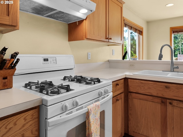 1305 Sandy Ridge Rd, Gearhart, OR 97138 - kitchen featuring white gas range oven, exhaust hood, light countertops, brown cabinets, and recessed lighting