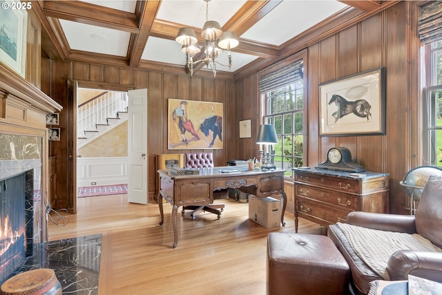 home office with a chandelier, coffered ceiling, a high end fireplace, beam ceiling, and light wood finished floors