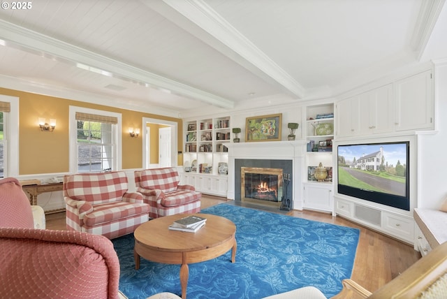 living area featuring light wood-style flooring, a fireplace with flush hearth, built in features, ornamental molding, and beam ceiling