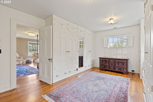 bedroom with light wood-style flooring, visible vents, baseboards, and a closet