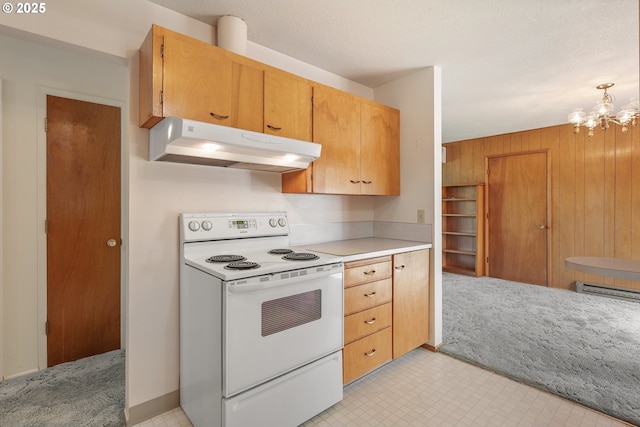 1088 Nopal St, Florence, OR 97439 - kitchen with under cabinet range hood, a chandelier, wooden walls, light countertops, and electric stove